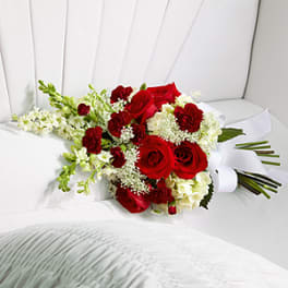 Red roses and white flowers arranged on a white chair