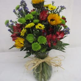Mixed bouquet in a glass vase with bright yellow, red, green, and purple flowers