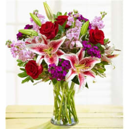 Bouquet of red roses and pink lilies in a clear glass vase