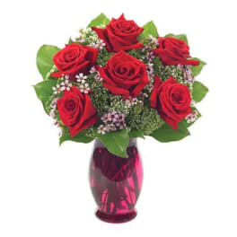 Red roses in a pink glass vase with small filler flowers