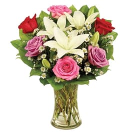 Bouquet of pink and red roses with white lilies in a glass vase