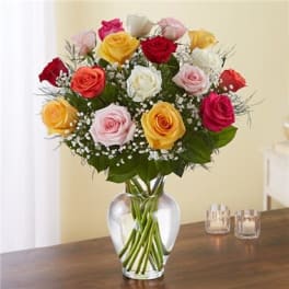 Mixed roses in pink, red, yellow, and white arranged in a clear glass vase