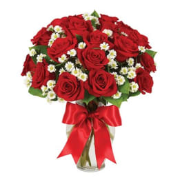 Red roses and white daisies in a glass vase with a red ribbon