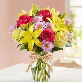 Bouquet of pink roses and yellow lilies in a clear glass vase