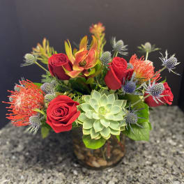 Red roses and a green succulent in a glass vase with spiky accent flowers