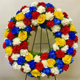 Circular wreath of red, white, blue, and yellow flowers on a stand