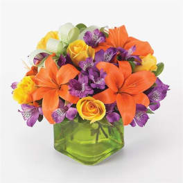 Orange lilies and purple alstroemeria in a green glass vase