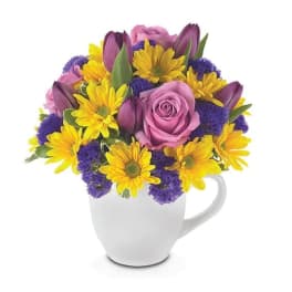 Pink roses and yellow daisies in a white mug vase