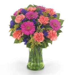 Mixed pink, purple, and coral flowers in a green glass vase