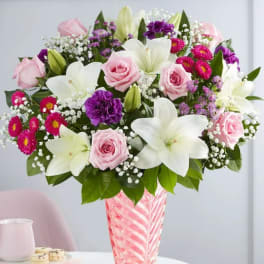 Pink roses and white lilies in a pink glass vase