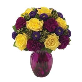 Bouquet of yellow roses and purple flowers in a magenta vase