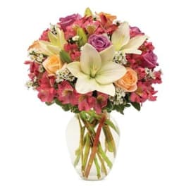 Mixed bouquet of lilies, roses, and pink flowers in a clear glass vase