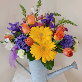 Colorful bouquet in a watering can with yellow daisies and orange roses
