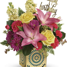 Mixed bouquet with pink lilies, yellow roses, and purple flowers in a decorative box