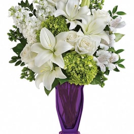 White lilies and roses arranged in a purple vase