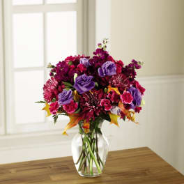 Purple and magenta mixed bouquet in a clear glass vase