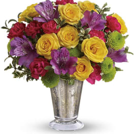 Bouquet of yellow and purple flowers in a clear glass vase