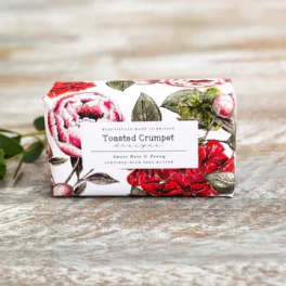 Wrapped bar of soap with a floral print label on a wooden surface