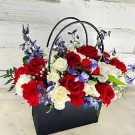 Basket arrangement of red and white roses with blue flowers