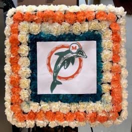 Square floral display with orange, white, and blue flowers around a logo