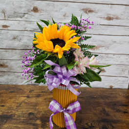 Sunflower bouquet in a pencil vase with purple ribbon and pink accent flowers