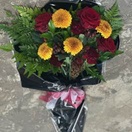 Bouquet of red roses and yellow chrysanthemums wrapped in black paper