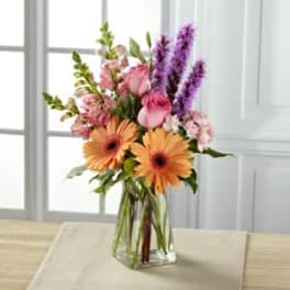 Bouquet of pink and orange flowers in a clear glass vase