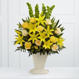 Yellow flowers and cream roses in a white pedestal vase