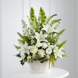 White lilies and roses arranged in a white basket