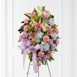 Standing floral spray with pink lilies, carnations, and pastel blooms on an easel