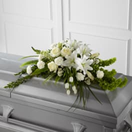 White floral spray arranged on a gray casket
