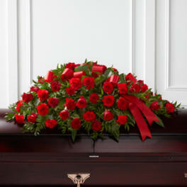 Red rose and carnation casket spray with a red ribbon
