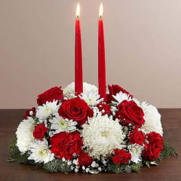 Red candles in a red, white, and green floral centerpiece