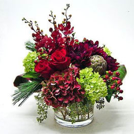 Red roses and burgundy flowers in a clear glass vase