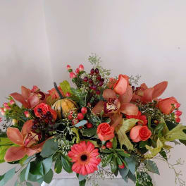 Coral floral arrangement with roses, orchids, and a gerbera daisy