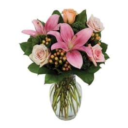 Pink lilies and pale roses arranged in a clear glass vase