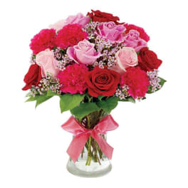 Bouquet of red and pink roses in a glass vase with a pink ribbon