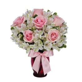 Pink roses and white alstroemeria in a red vase with a pink ribbon