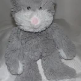 Gray plush teddy bear with a pink nose sitting on a bed
