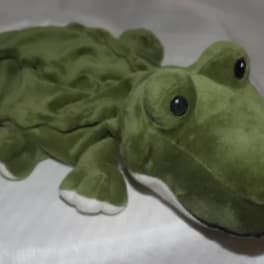Plush green frog toy with large eyes lying on a light surface