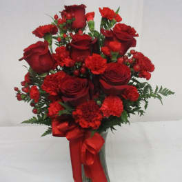 Red roses and carnations in a glass vase with a red ribbon