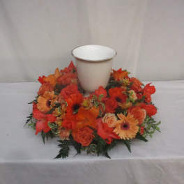 Orange floral wreath around a white urn-shaped vase