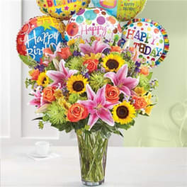 Bouquet of mixed flowers with birthday balloons in a glass vase