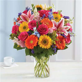 Mixed bouquet of pink roses, lilies, and gerbera daisies in a glass vase