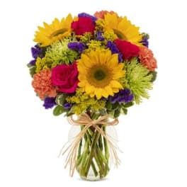 Bouquet of sunflowers, roses, and mixed blooms in a glass vase