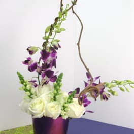 White roses and purple orchids in a metallic vase