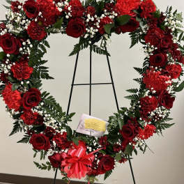 Heart-shaped red floral wreath on an easel with a pink bow
