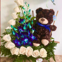 White roses arranged with a teddy bear and blue-purple orchids