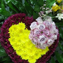 Heart-shaped floral arrangement with yellow, purple, and pale pink flowers