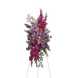 Tall floral spray with pink lilies and purple flowers on a white stand